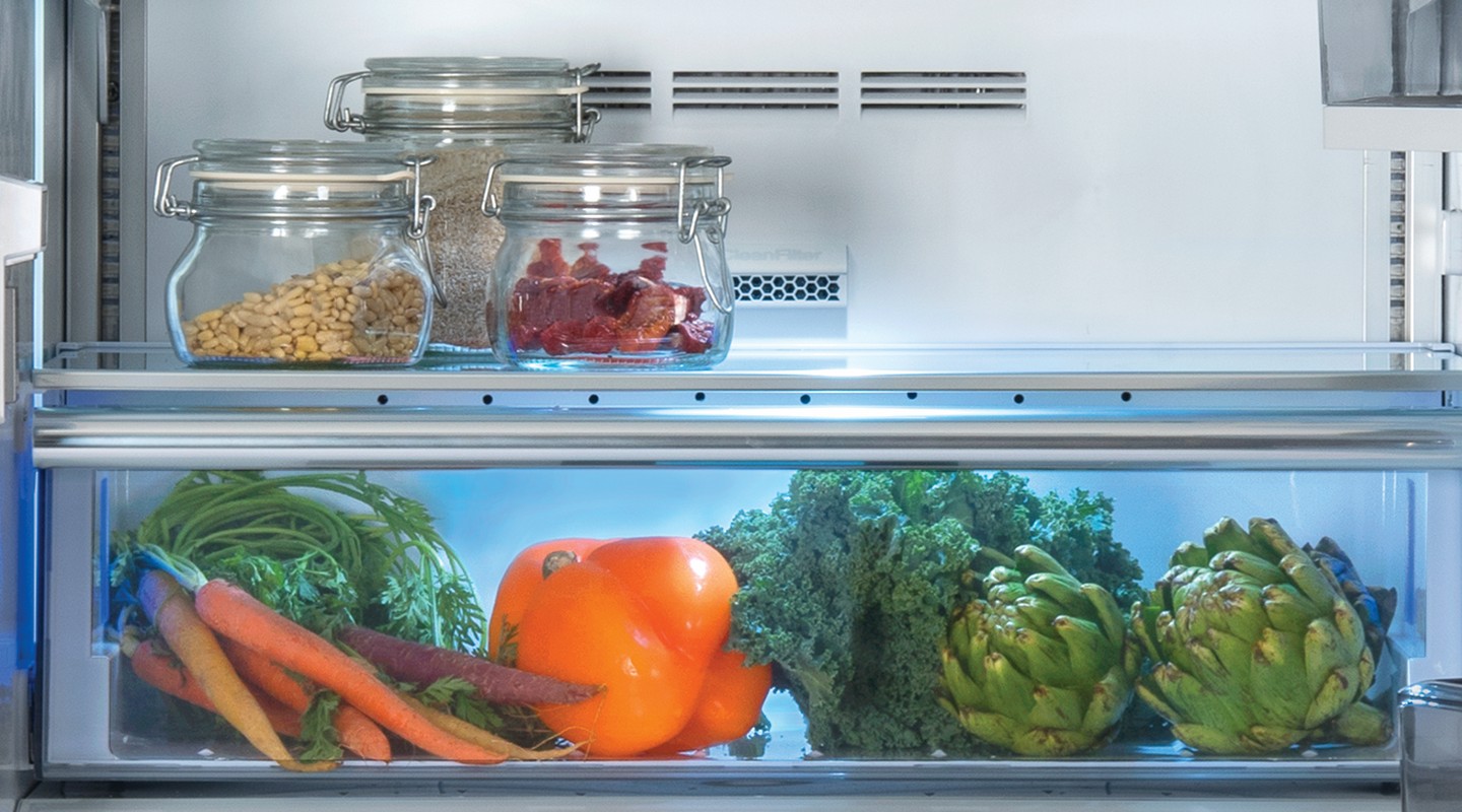 Integrated kitchen with an open Beko refrigerator full of fresh food
